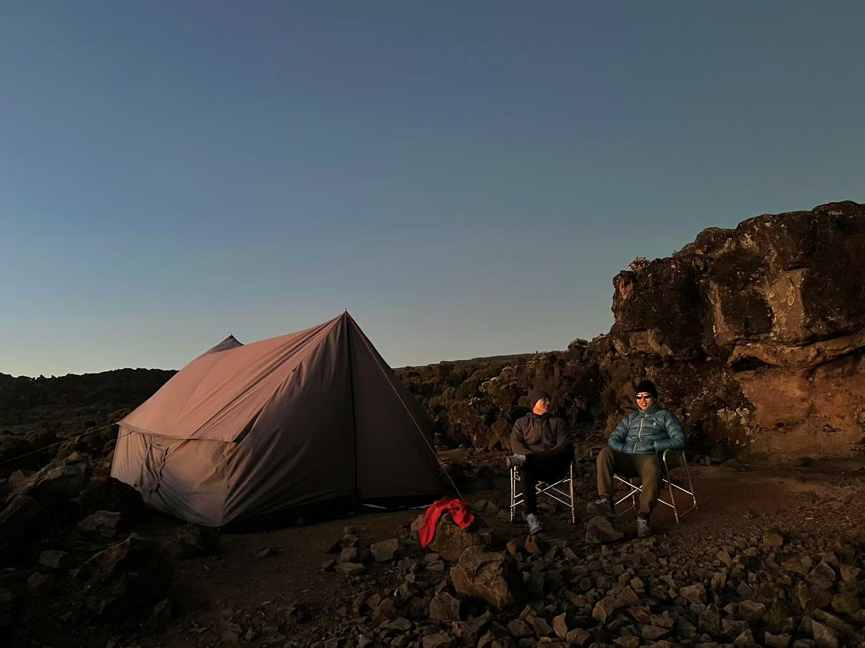 Climbers relaxing outside their tent at dusk on Kilimanjaro